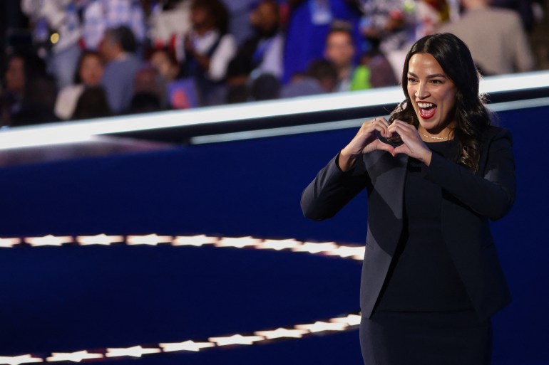 Alexandria Ocasio Cortez flashes a heart with her hands.