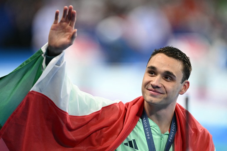 Gold medallist Hungary's Kristof Milak celebrates during the podium ceremony of the men's 100m butterfly swimming event during the Paris 2024 Olympic Games at the Paris La Defense Arena in Nanterre, west of Paris, on August 3, 2024. (Photo by Jonathan NACKSTRAND / AFP)