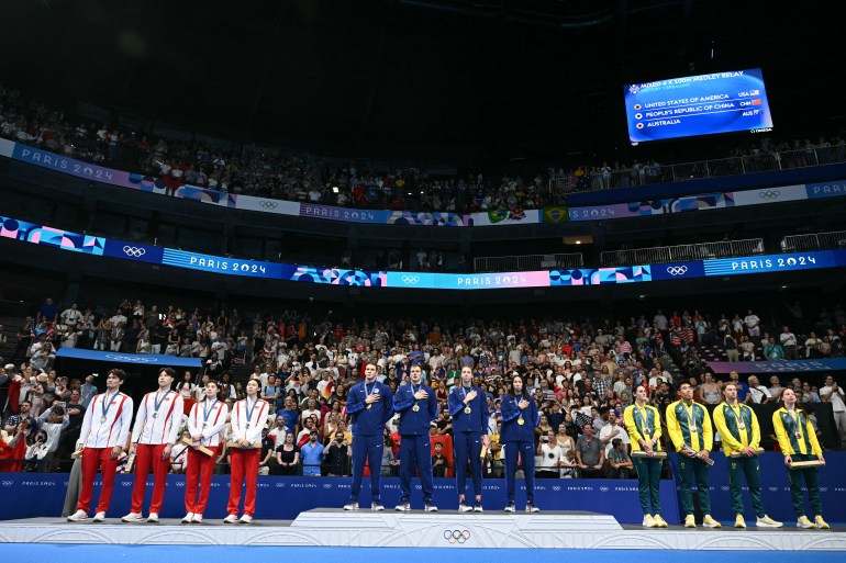 (L-R) Silver medallists China, gold medallists USA and bronze medallists Australia celebrate on the podium of the mixed 4x100m medley relay final swimming event during the Paris 2024 Olympic Games at the Paris La Defense Arena in Nanterre, west of Paris, on August 3, 2024. (Photo by SEBASTIEN BOZON / AFP)