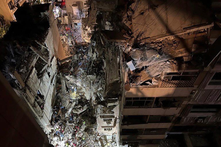 Civil defence workers and citizens gather near a destroyed building that was hit by an Israeli airstrike in the southern suburbs of Beirut, Lebanon