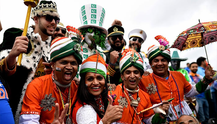 Indian fans in costume jump into the frame with Pakistani fans in costume in this undated photo. ─ AFP/File