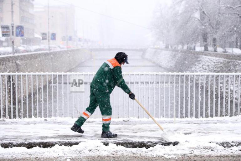 Utility worker cleans the snow during heavy snowfall in downtown Sarajevo, Bosnia, Monday, Dec. 23, 2024. (AP Photo/Armin Durgut)