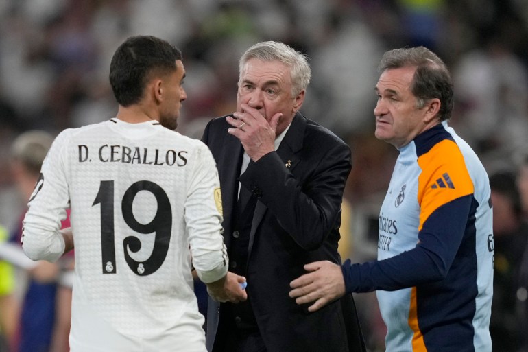 Real Madrid's head coach Carlo Ancelotti, centre, talks to Real Madrid's Dani Ceballos during the Spain Super Cup final soccer match between Real Madrid and Barcelona at King Abdullah Stadium in Jeddah, Saudi Arabia, Sunday, Jan. 12, 2025. (AP Photo/Altaf Qadri)